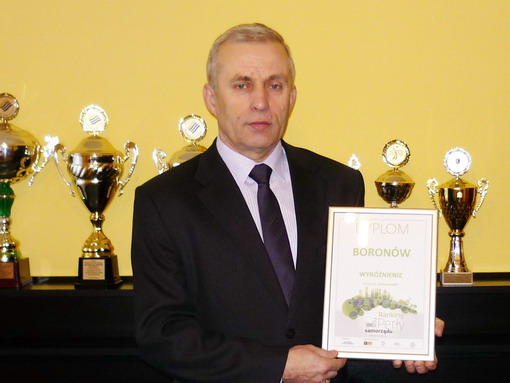 Przewodniczący Rady Gminy Edward Czyż prezentuje wyr&oacute;żnienie dla Gminy Boron&oacute;w w&nbsp;rankingu &bdquo;Perły Samorządu 2012&rdquo;. W tle widoczne są puchary.